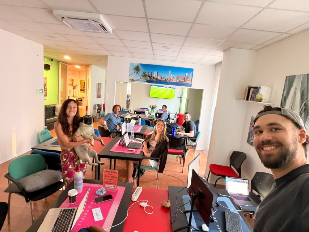 Members at laptops across the cowork floor in Bari, one holding a pug