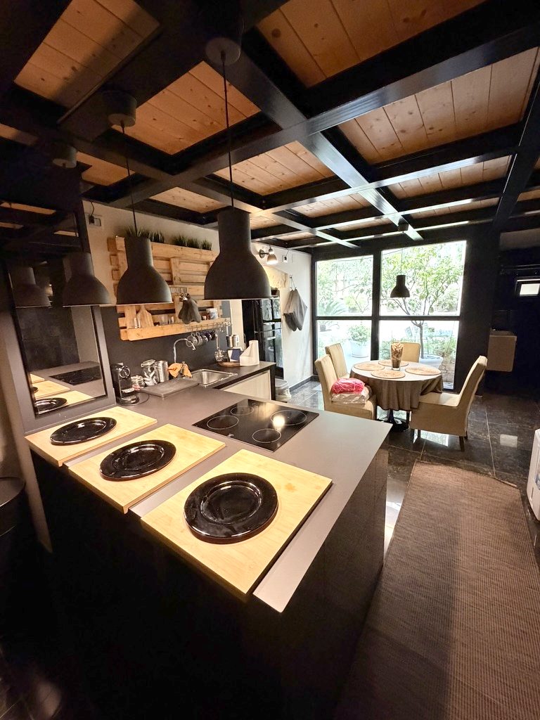 The same apartment: the kitchen under wooden beams, the garden through the glass