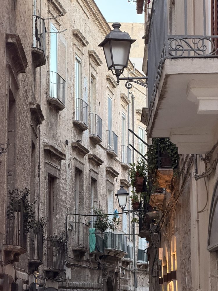A stone alley in old Bari with balconies and street lamps